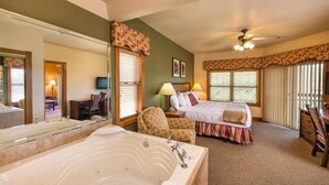 A hotel room with a large bathtub, a bed with a colorful bedspread, a chair, a desk, and a television. - Westgate Branson Woods NYE 2Bedroom Villa. (Branson)