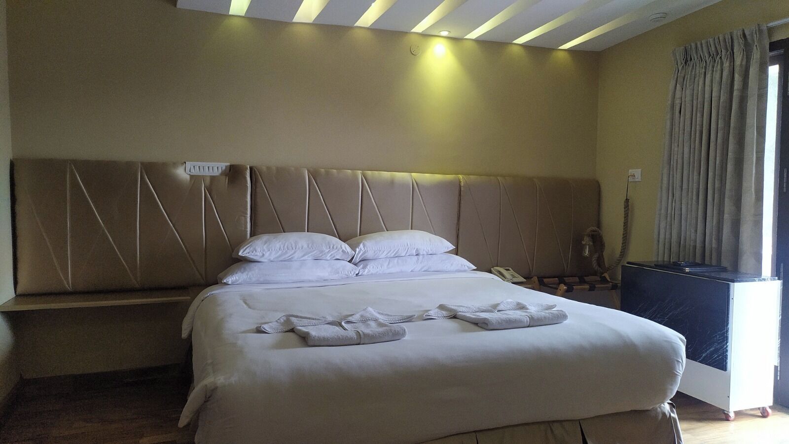 A hotel room with a large bed, a bedside table, a desk, and a chair.