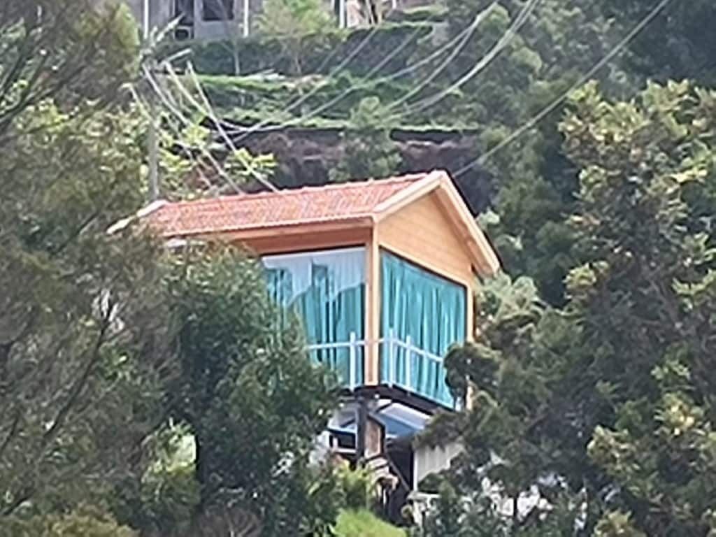 A small, elevated wooden structure with a red roof, surrounded by trees.