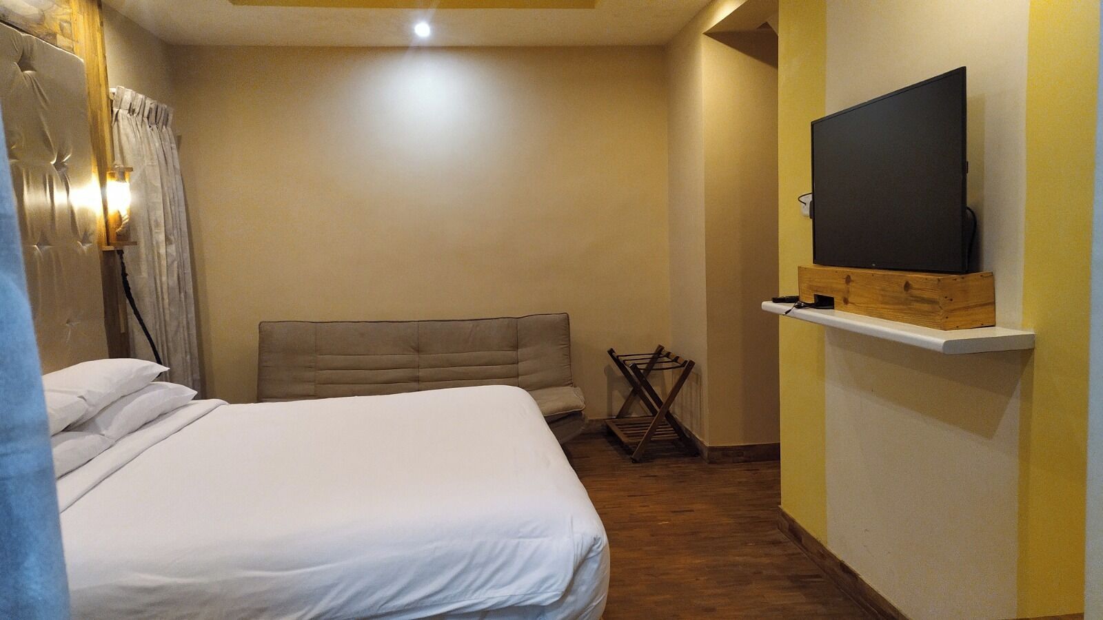 Ein Schlafzimmer mit einem Bett, einem Fernseher auf einem Regal und einem Holztrockner.