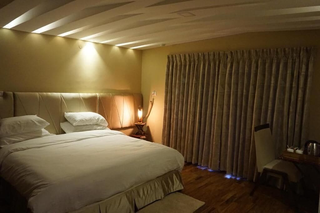 Ein Hotelzimmer mit einem großen Bett, einem Nachttisch mit Lampe und einem Sessel.