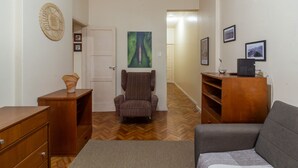 A compact living space with a wooden dresser, a striped armchair, a gray sofa, and a herringbone-patterned wooden floor. - 5 Minutes From Copacabana Beach Bi307 (Rio de Janeiro)