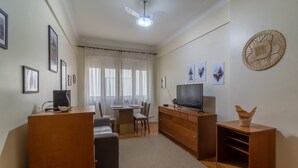A living room with a sofa, TV, wooden cabinets, a dining table with chairs, and a ceiling fan. - 5 Minutes From Copacabana Beach Bi307 (Rio de Janeiro)