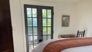 Ein Schlafzimmer mit einem Bett, einem dunklen Holzschrank, einem gemusterten Teppich und einer Tür, die nach draußen führt.