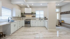 A modern kitchen with white cabinets, a built-in oven, and a stainless steel range hood. - Casa Francesca 6BR Villa & Heated Pool (Roselle)