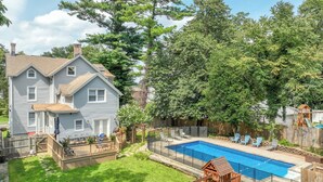 A backyard with a swimming pool, a wooden deck, and a swing set. - Casa Francesca 6BR Villa & Heated Pool (Roselle)