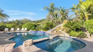 A swimming pool with a hot tub, surrounded by palm trees and a stone wall. - Hilltop Villa_Amazing Pool+Views (Fallbrook)