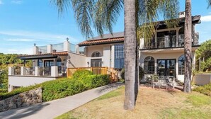 A two-story house with a patio, a stone wall, and a palm tree. - Hilltop Villa_Amazing Pool+Views (Fallbrook)