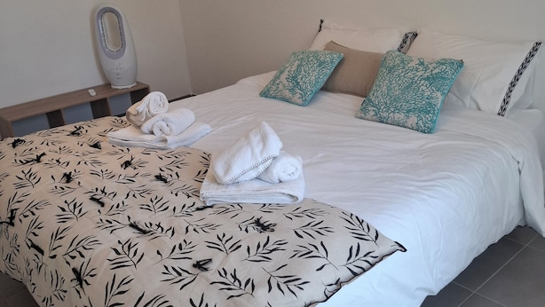A neatly made bed with white linens, a patterned throw blanket, and decorative pillows. - Quiet apartment near the beaches—relaxation guaranteed with air conditioning (Six-Fours-les-Plages)