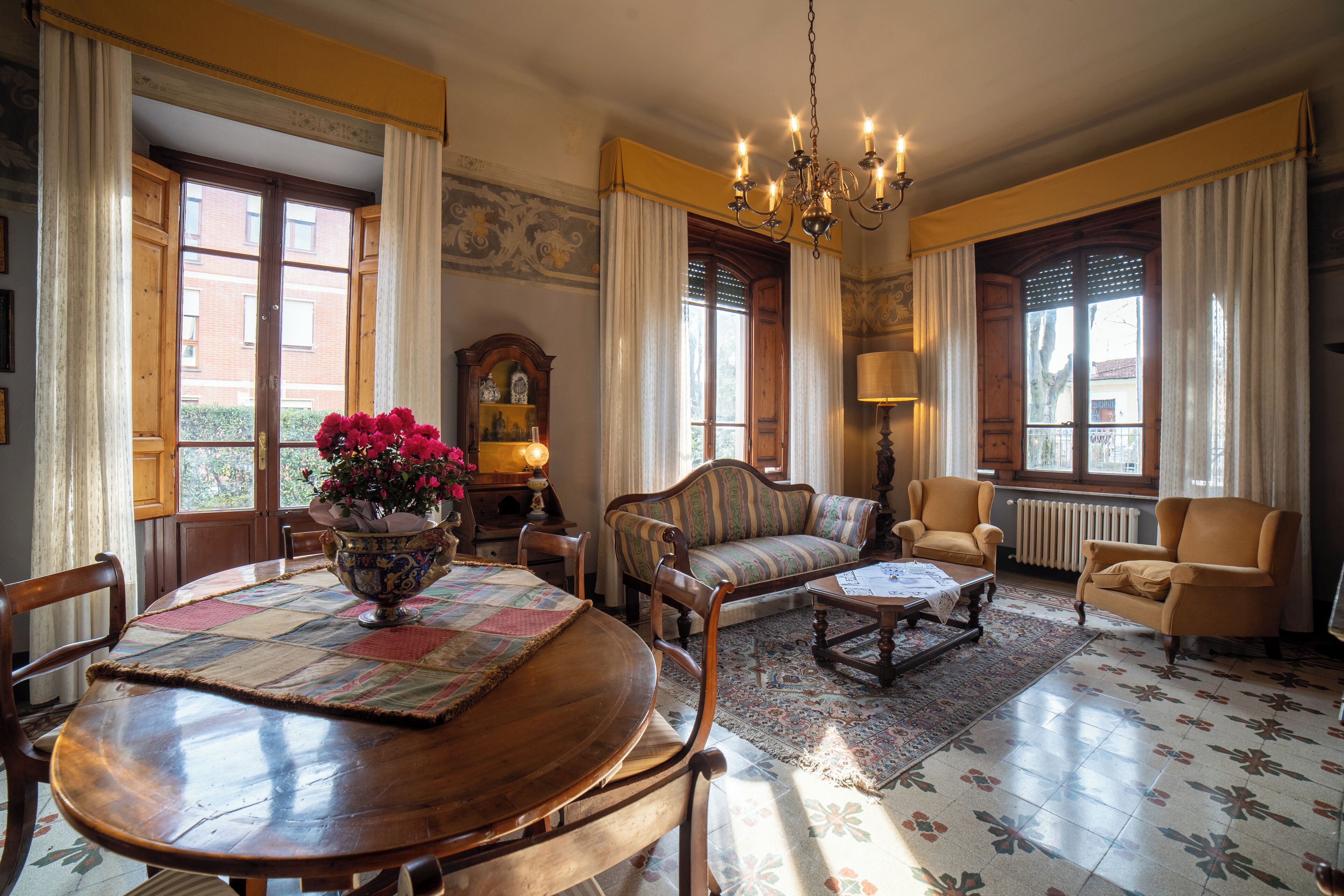A traditional room with a wooden dining table, a sofa, and two armchairs.