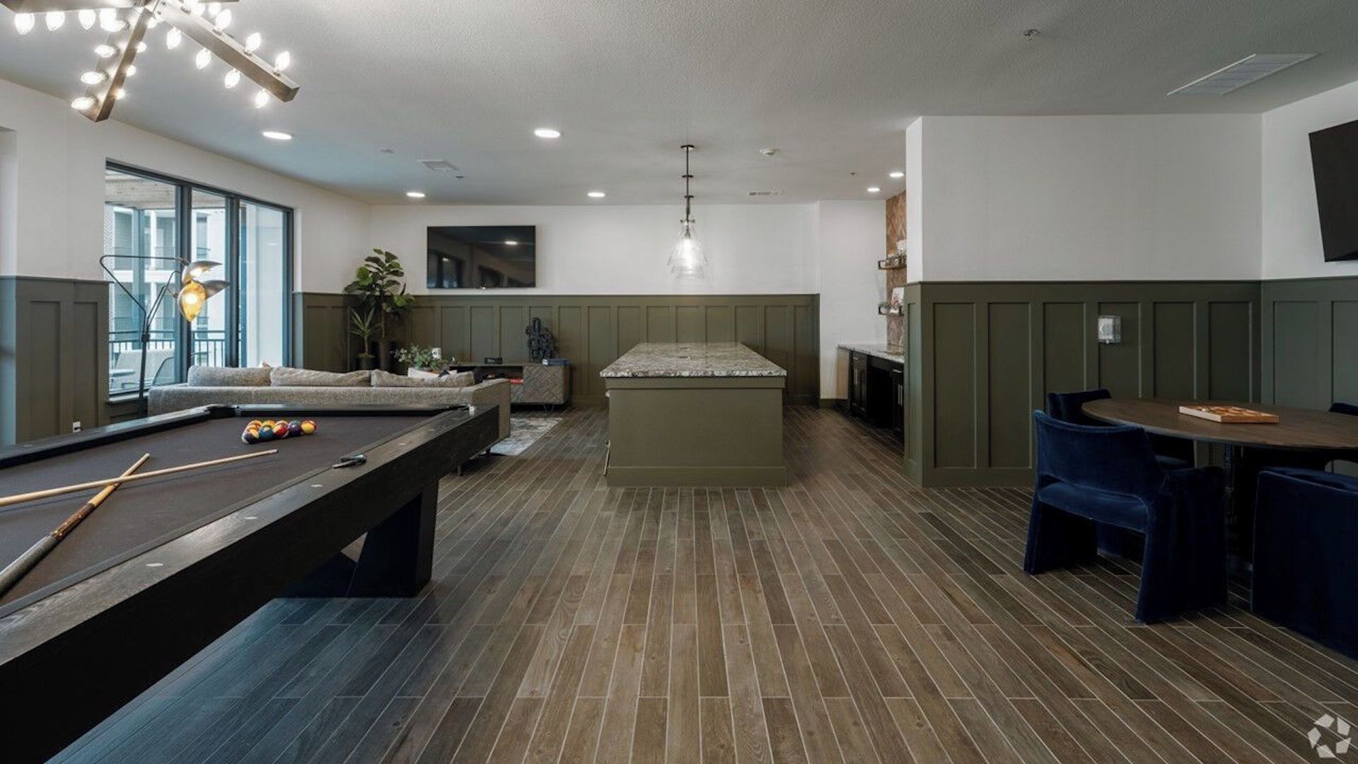 A modern indoor space with a pool table, seating area, and a bar.