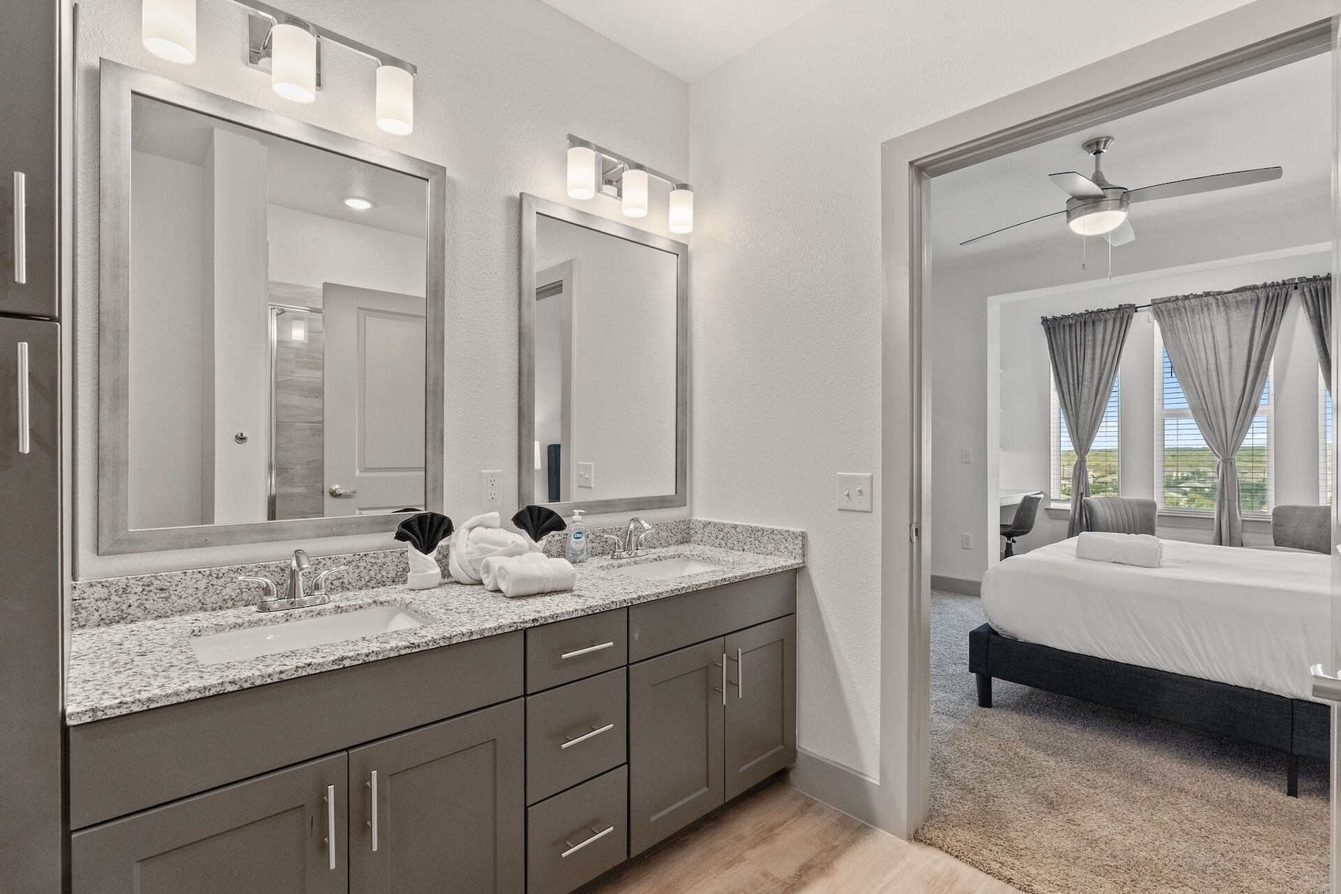 Un baño moderno con lavamanos doble, espejos amplios y tocador con encimera de granito.