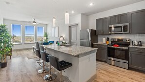 A modern kitchen with a central island, stainless steel appliances, and a view of the outdoors. - Luxury 2BD/2BA Next to Airport ziix (Del Valle)