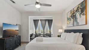 A hotel room with a large bed, a desk with a chair, a television, and a ceiling fan. - Luxury 2BD/2BA Next to Airport ziix (Del Valle)