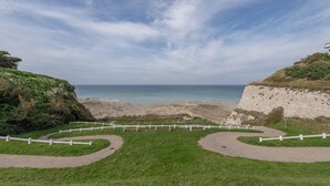 A coastal landscape with a curved pathway and white railings leading to the beach. - Le Reflet de l'Horizon - Proche Plage (Saint-Quentin-la-Motte-Croix-au-Bailly)