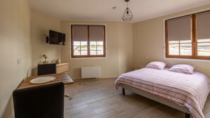A bedroom with a bed, a desk, a chair, a TV, and large windows. - Le Reflet de l'Horizon - Proche Plage (Saint-Quentin-la-Motte-Croix-au-Bailly)