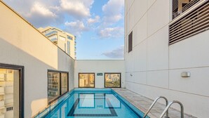 A rooftop swimming pool with clear blue tiles, surrounded by white walls and large windows. - Modern, well located in Sampa next to the Faria Lima subway station (São Paulo)