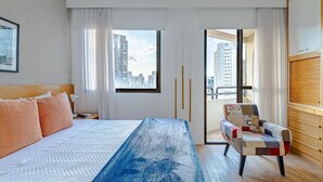 A modern hotel room with a large bed, a view of the city through a glass door, and a wooden dresser. - Modern, well located in Sampa next to the Faria Lima subway station (São Paulo)