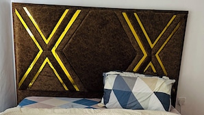 A bed with a quilted headboard, a patterned pillow, and a polka-dotted duvet. - Osim homes (Arusha)