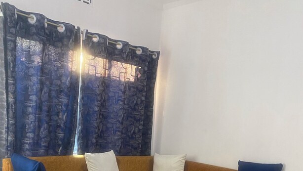 A living room with a sectional sofa, a round coffee table, and a patterned rug. - Osim homes (Arusha)