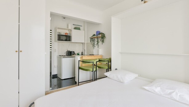 A compact bedroom with a bed, a small kitchenette, and a desk area.