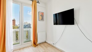 A room with a sliding glass door, a mounted TV, and a framed picture on the wall.