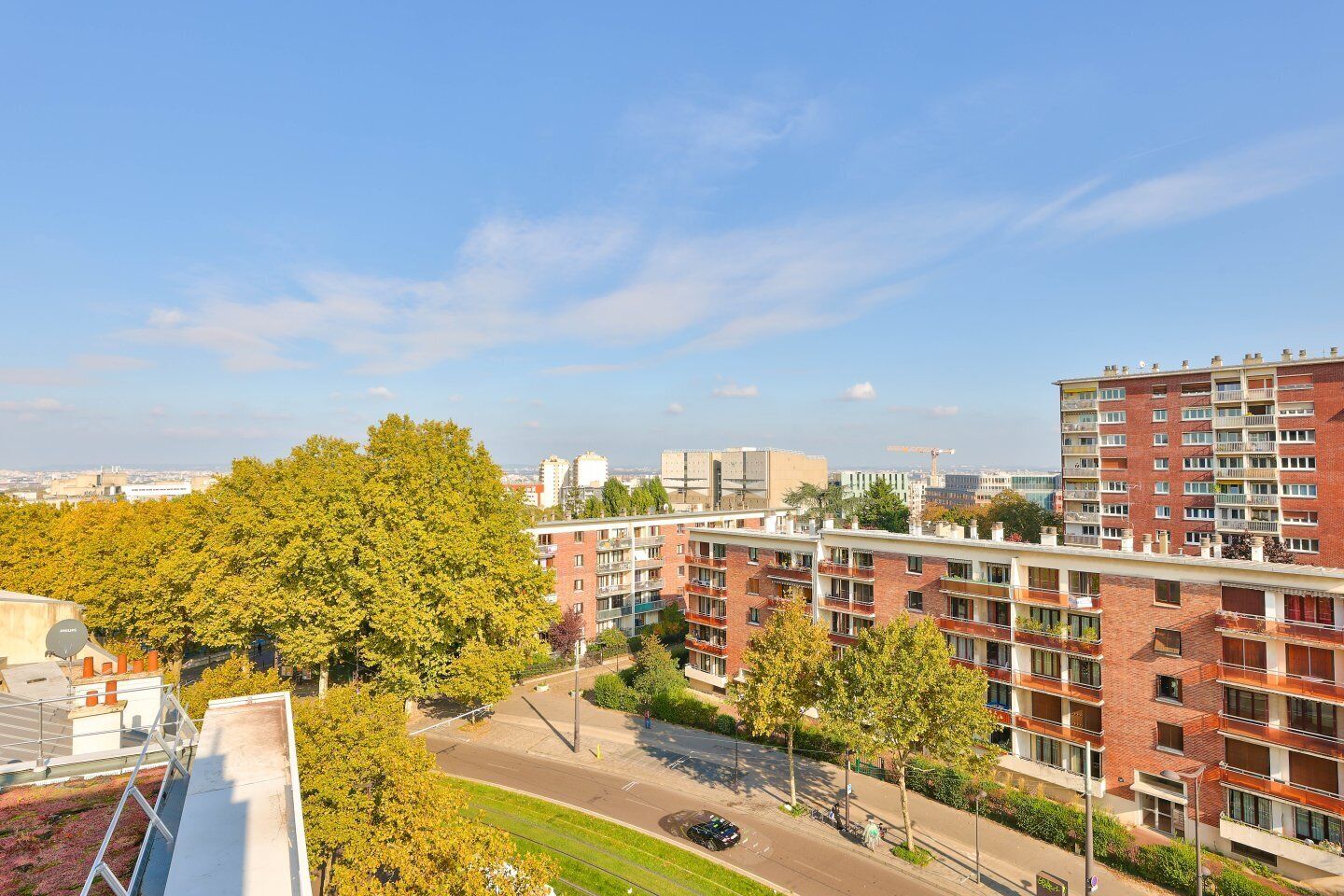Een meerlaags woongebouw met balkons, een parkeerplaats en een heldere lucht.