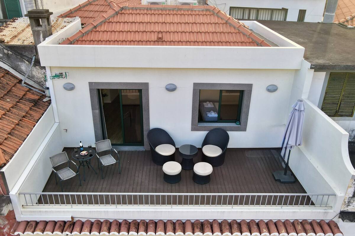 A balcony with a table and chairs, a small window, and a door.