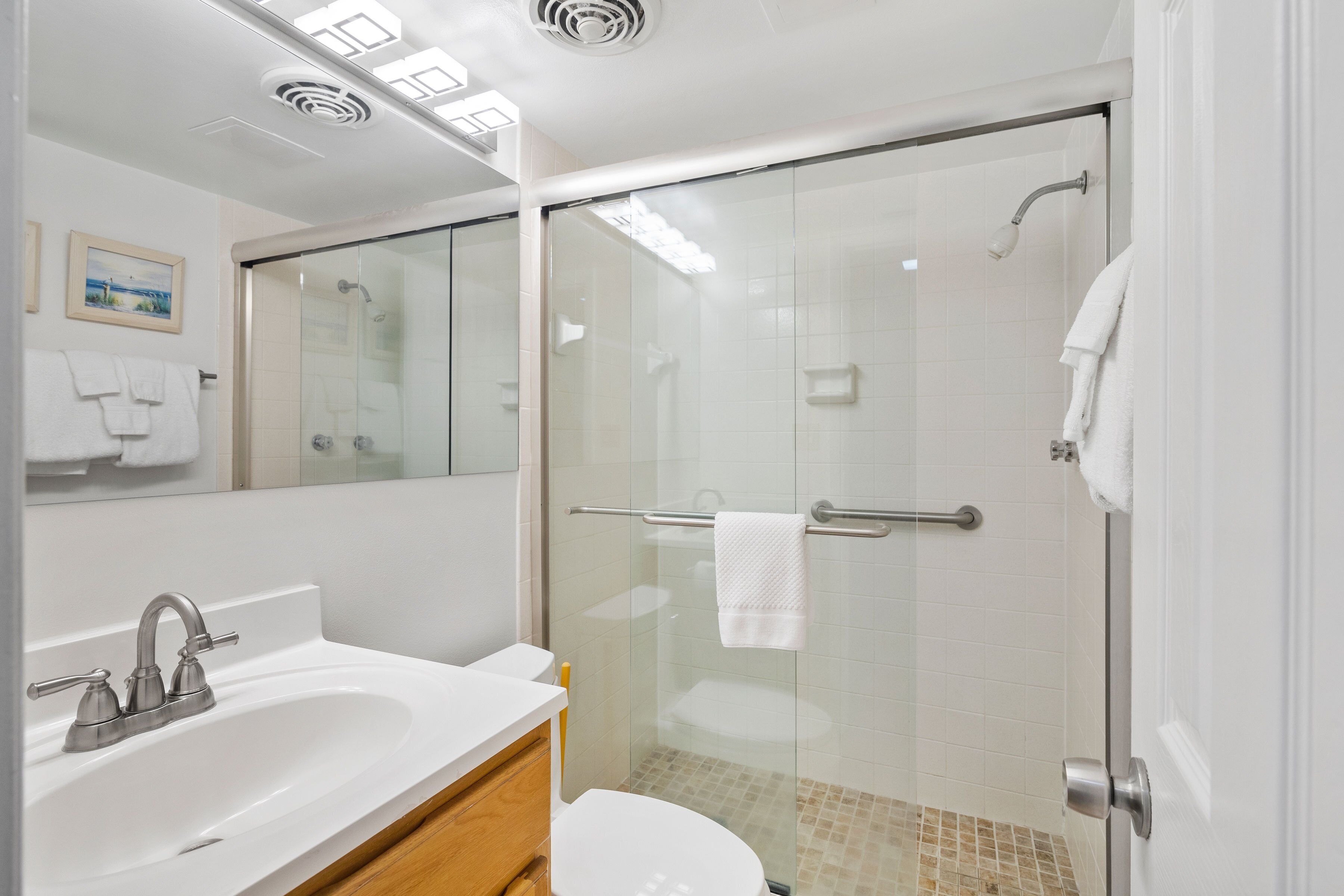 A modern bathroom with a glass-enclosed shower, a white sink, and a toilet.