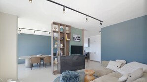 Una sala moderna con un sofá, un reposapiés y un comedor con mesa y sillas.