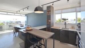 Una cocina moderna con una isla central, taburetes de bar, una lámpara colgante y vistas de la ciudad.