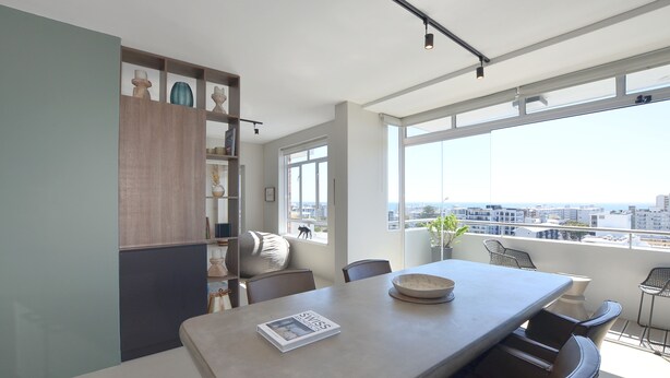 Un comedor moderno con una mesa grande, sillas y vistas de la ciudad a través de amplias ventanas.