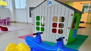 A play area with a house, a yellow rocking horse, and a blue boat.