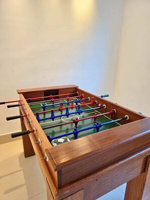 A wooden foosball table with a green playing surface. - Apartment with full leisure facilities, air conditioning in the rooms and Wi-Fi (Ubatuba)