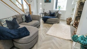 A modern living room with two sofas, a herringbone-patterned floor, a fireplace, and a large window. - Rhows (Llanfairpwllgwyngyll)