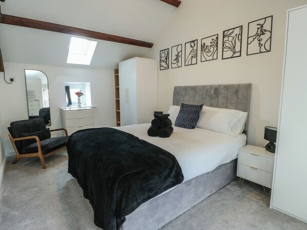 Une chambre à coucher comprenant un lit, une table de chevet, une chaise, une armoire et une œuvre d’art accrochée au mur.
