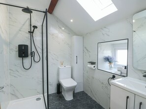 A modern bathroom with a shower, toilet, and sink, featuring marble walls and a skylight. - Rhows (Llanfairpwllgwyngyll)