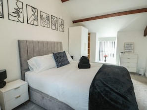 A bedroom with a bed, bedside tables, a wardrobe, a window with curtains, and wall art.