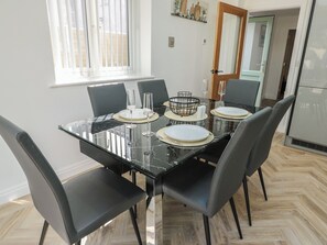 A dining table with six chairs, a black marble top, and a white door in the background. - Hen Siop (Llanfairpwllgwyngyll)