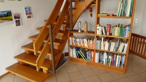 A staircase with wooden steps and a wooden railing, leading to a bookshelf filled with books. - Holiday Home "Unteres Hart" – Spacious and Comfortable (Gomadingen)