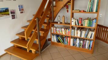 Eine Treppe mit Holzboden und Geländer, die zu einem Bücherregal mit Büchern führt.