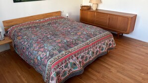 A bedroom with a wooden bed, a wooden dresser, and two landscape paintings on the wall. - Holiday Home "Unteres Hart" – Spacious and Comfortable (Gomadingen)