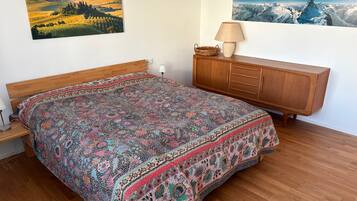 Ein Schlafzimmer mit einem hölzernen Bett, einer Holzkommode und zwei Landschaftsbildern an der Wand.