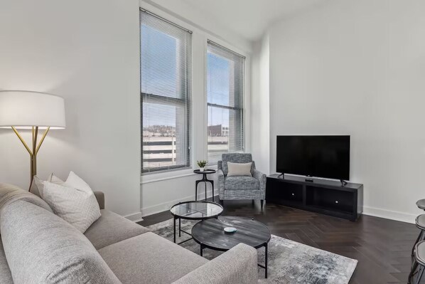 A modern living room with a sofa, coffee table, TV, and a chair.