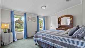 Ein Schlafzimmer mit einem großen Bett, einem Nachttisch mit Lampe, einem Schminktisch und einem Spiegel.