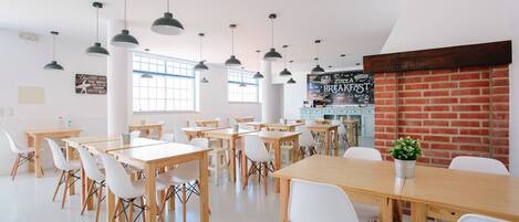Un grand espace dédié à la salle à manger, avec plusieurs tables et chaises, un mur en briques et un tableau noir servant de menu.
