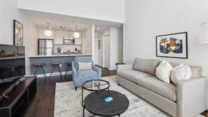 A modern living room with a sofa, coffee table, and a dining area with bar stools. - Union Station Stay | Spacious Unit w/ Kitchen | Walk to Parks & Museums (Pittsburgh)