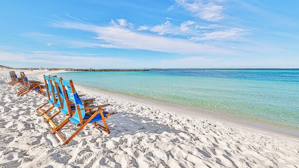 Ein Strand mit Reihen blauer Liegestühle und einem wolkenlosen, blauen Himmel.
