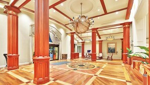 Eine prachtvolle Lobby mit hohen Holzsäulen, einem großen Chandelier und einem aufwendigen Fußbodenmuster.