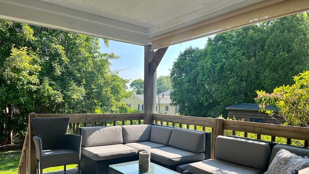 A covered outdoor seating area with wicker furniture and a glass-top table. - Marvelous 4-bedroom, 2-bath home with AC and private backyard close to the beach (Narragansett)
